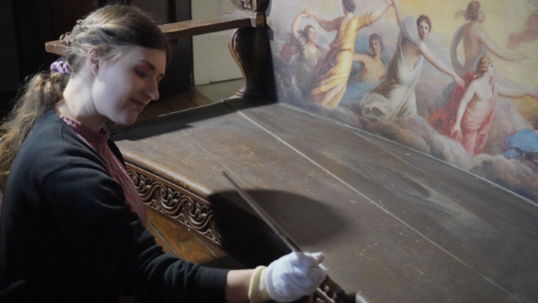 A conservation assistant cleaning the Apollo bench which will be on display in the house.